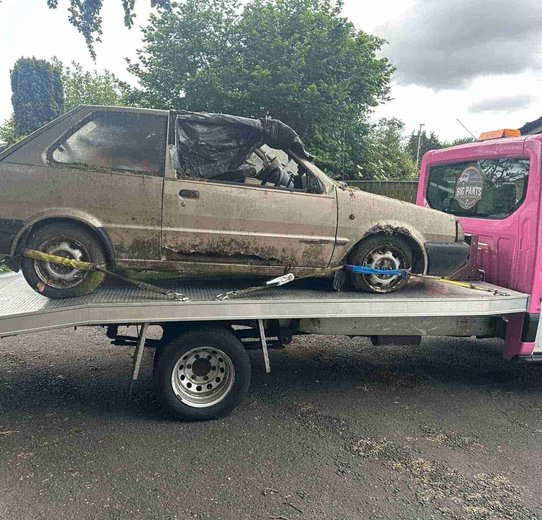 Abanonded car being loaded on pink truck