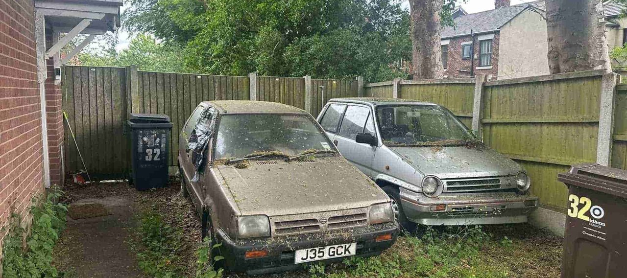 A pair of cars rotting away in a corner