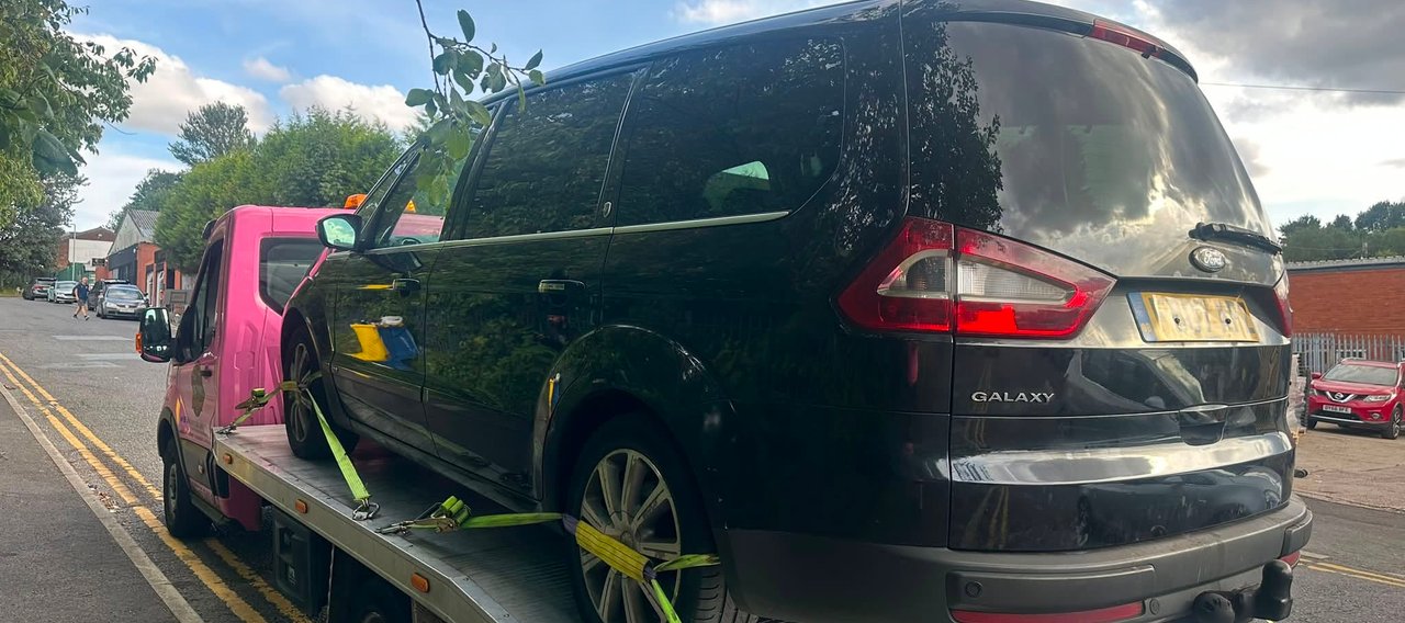 black car being moved by pink truck